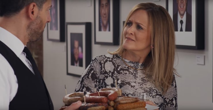 A waiter offering sausages to Samantha Bee