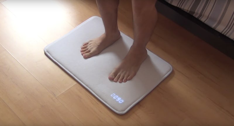 A person standing on a snooze-proof mat alarm clock