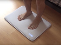 A person standing on a snooze-proof mat alarm clock