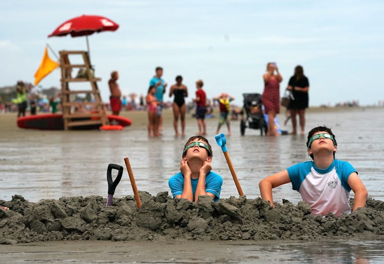 Two boys at the beach looking up and watching the eclipse