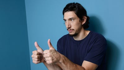 Adam Driver holding two thumbs up next to a blue wall