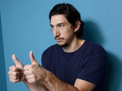 Adam Driver holding two thumbs up next to a blue wall