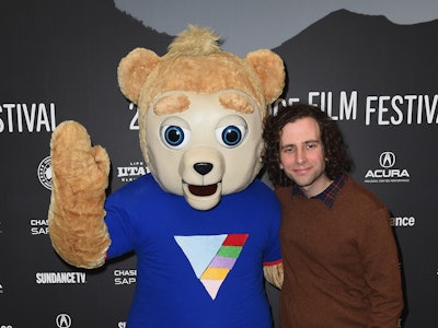 Kyle Mooney next to a person wearing a Brigsby Bear costume posing on the red carpet