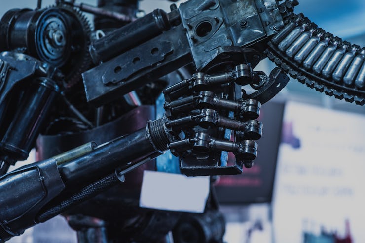 A closeup of the hand of a killer robot holding a machine gun