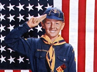 Boy Scout Merit Badges smiling in front of the United States flag