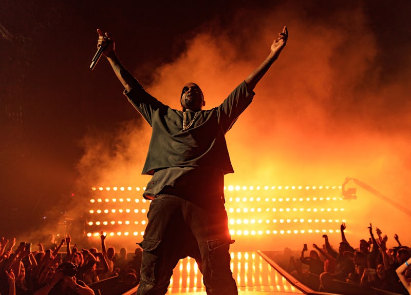 Kanye West performing on stage with red steam behind him 