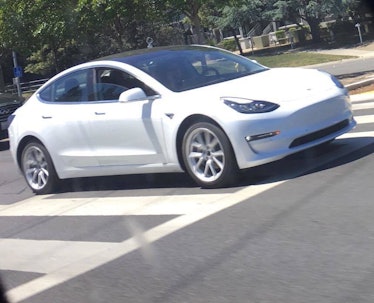 A white Model 3 out on the streets. Note the lip running across the doors.