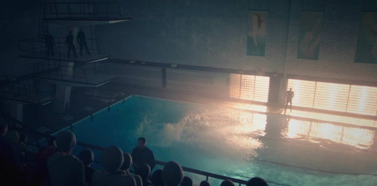 An indoor pool with a large audience and two people standing on the diving board
