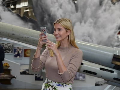Ivanka Trump smiling while looking at her grey iPhone 