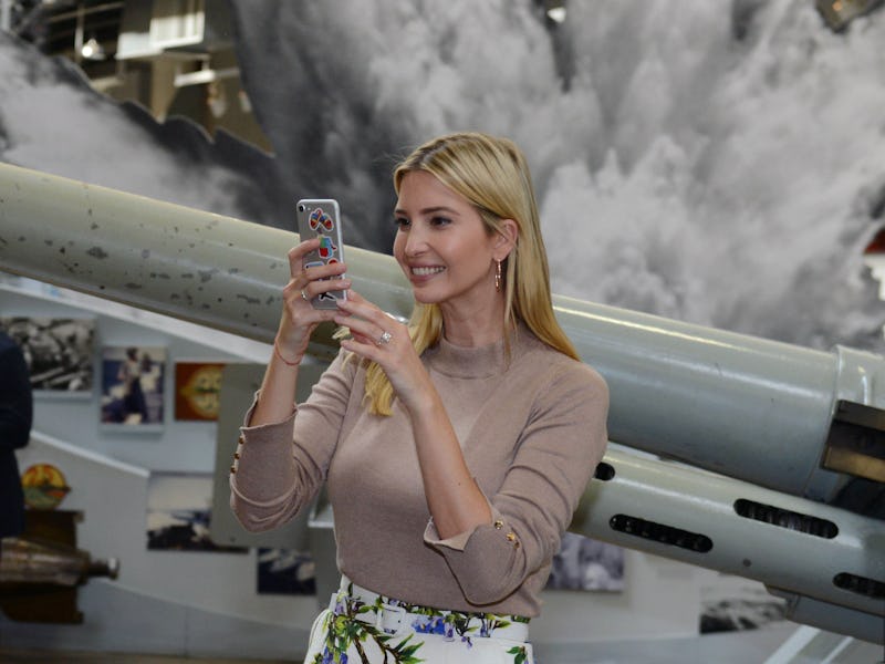 Ivanka Trump smiling while looking at her grey iPhone