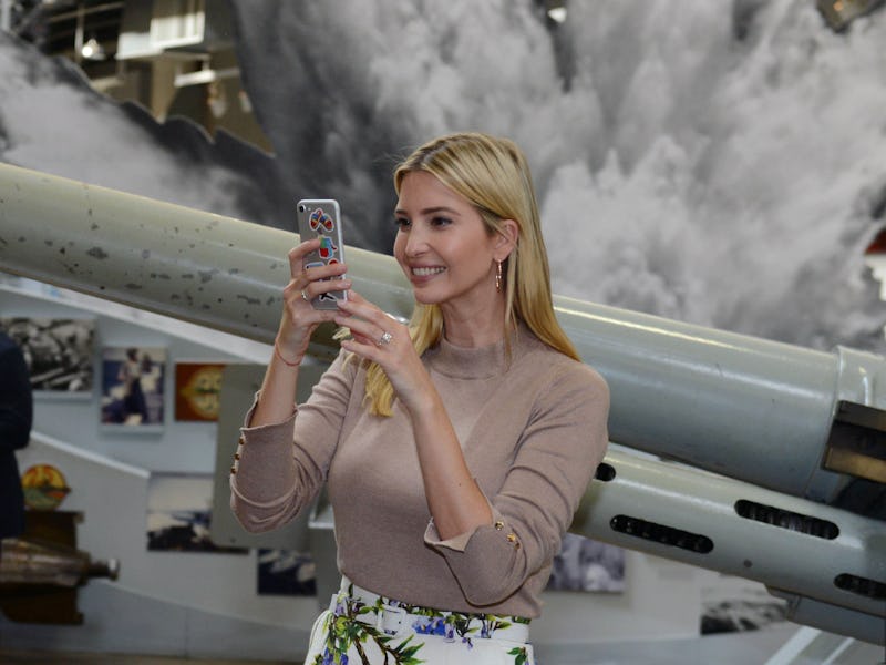 Ivanka Trump smiling while looking at her grey iPhone 