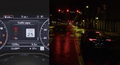 An audi dashboard next to the view of a street at night