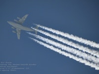 A plane flying through the sky leaving chemtrails behind it