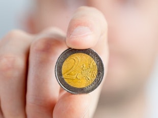 A hand holding a two Euro metal coin