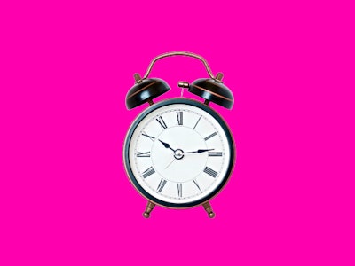 An alarm clock on a pink background 