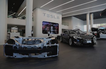 Tesla prototype vehicle next to Tesla model S vehicle at a Tesla showroom