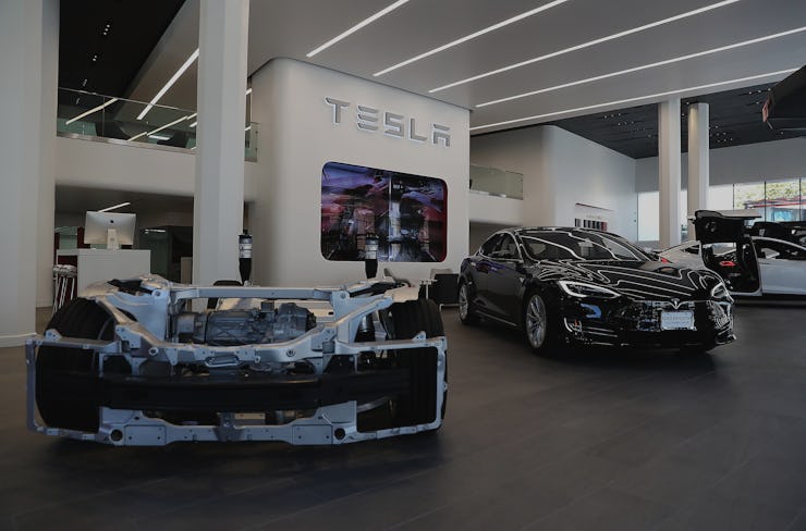 Tesla prototype vehicle next to Tesla model S vehicle at a Tesla showroom