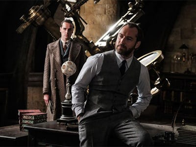 New photo of Jude Law's Dumbledore sitting on the wooden table in his office with hands in his pocke...