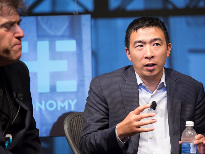 Andrew Yang being interviewed while wearing a black suit and a blue shirt