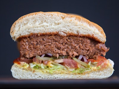 A closeup of a half-sliced plant based burger