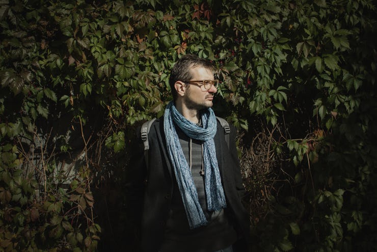 A man posing in under-$15 men's winter wear - a jacket, sweater and a scarf.