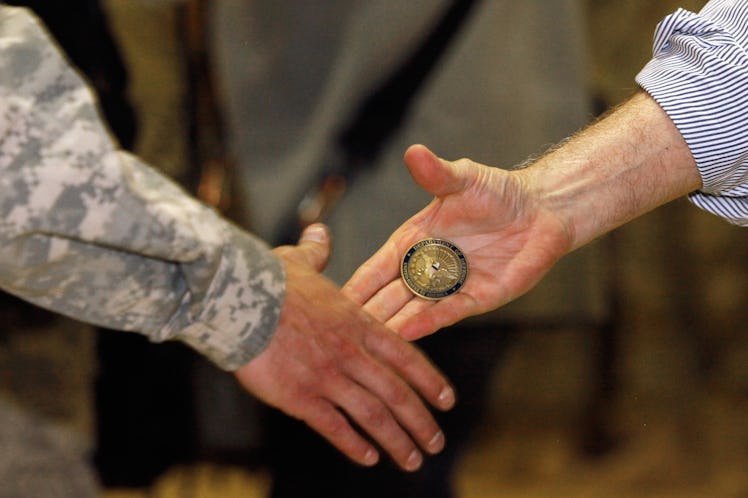 U.S. Defense Secretary Robert Gates presents a 'challenge coin' while shaking hands and posing for p...