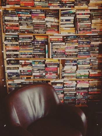 A shelf full of books next to an armchair