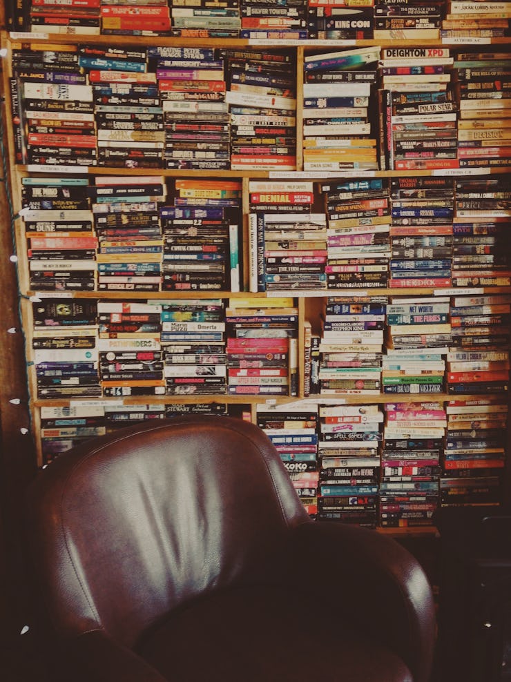 A shelf full of books next to an armchair