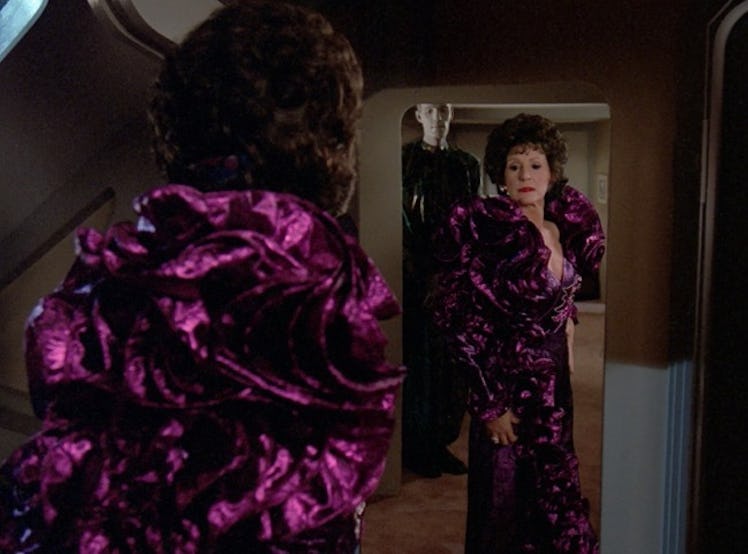 A woman checking herself out in a mirror in a big purple puffed velvet dress