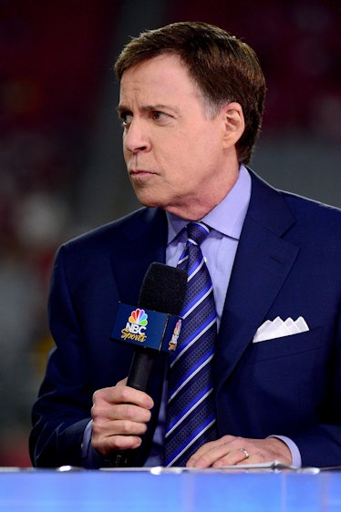 A commentator is standing holding an NBC microphone with a confused look on his face.