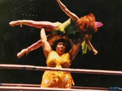 Mountain Fiji holding Godiva over her head during a wrestling match