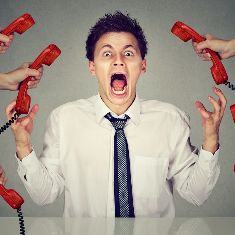 A distracted and angry man yelling in a white shirt with hands holding red phones around him