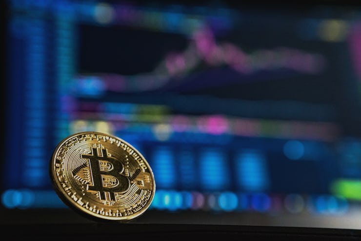 A BITCOIN with a blurred PC monitor with an opened graph