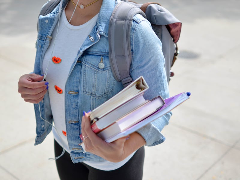 A girl in a white shirt and a blue denim jacket, wearing a grey back to school backpack under $100