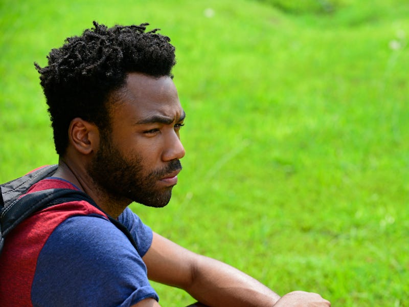 Donald Glover in "Atlanta" sitting in a blue-orange-black shirt on grass