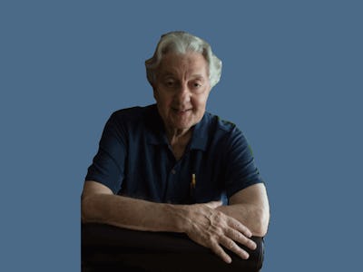 Dr. Herbert Kleber standing, leaning against a chair on a blue background 