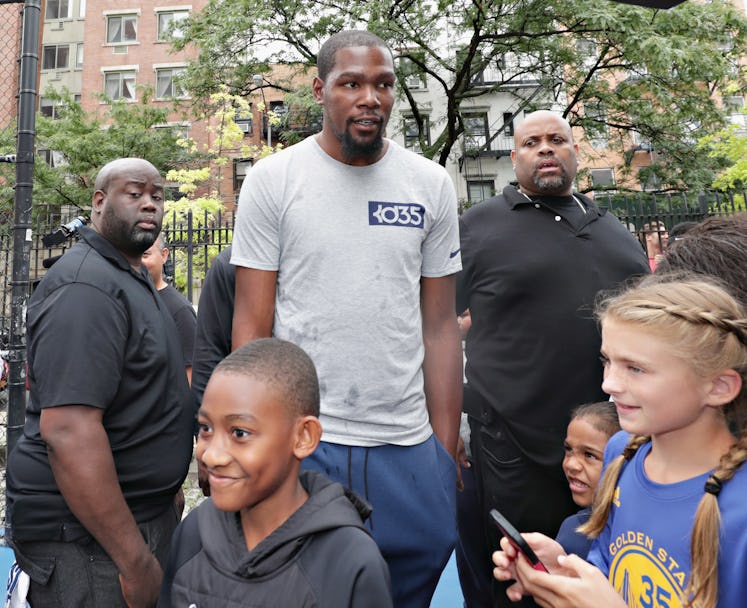 Kevin Durant at an outdoor basketball court surrounded by kids