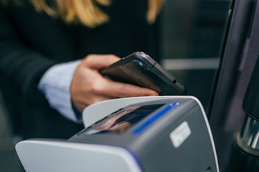 A woman holding a phone next to a credit card machine