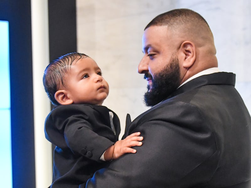 DJ Khaled holding his son while both are wearing black suits.