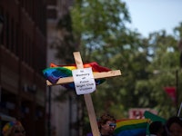 A wooden cross with the pride flag in the back and a sign for the Pulse night club victims