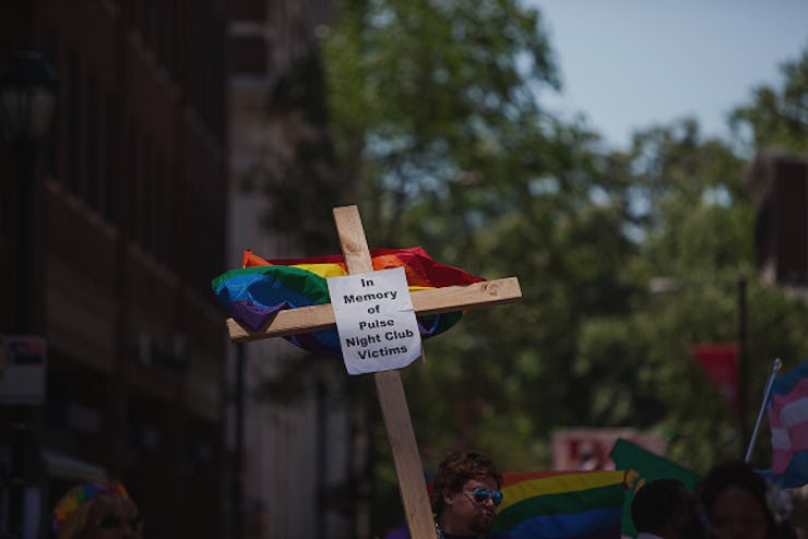A wooden cross with the pride flag in the back and a sign for the Pulse night club victims
