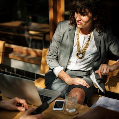 A woman in a grey suit sitting on a wooden bench, who can benefit from being kind