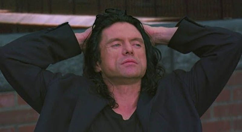 Tommy Wiseau from 'The Room' in a black suit with his hand on his head