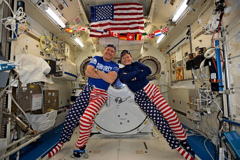 Two astronauts smiling and posing while celebrating the fourth of July in space