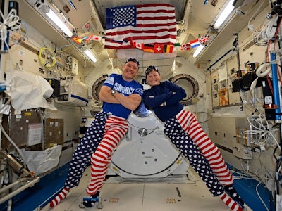 Two astronauts smiling and posing while celebrating the fourth of July in space