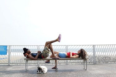 A boy and a girl lying on a bench at the Rockaway Beach in Queens