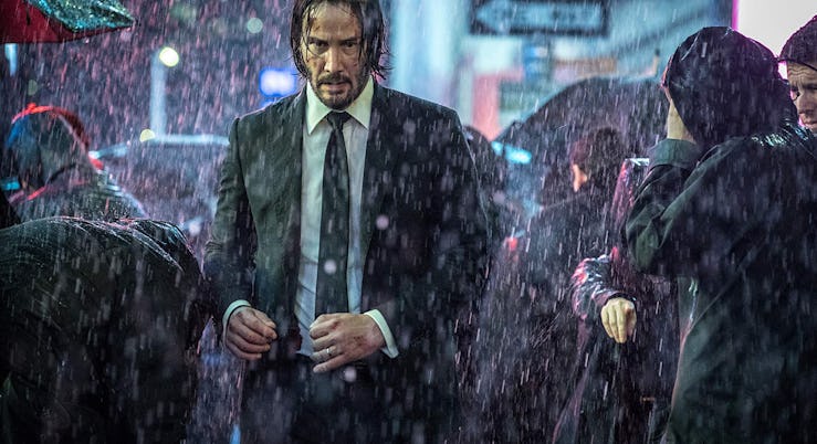Keanu Reeves walking through a crowd in the rain in John Wick 4 