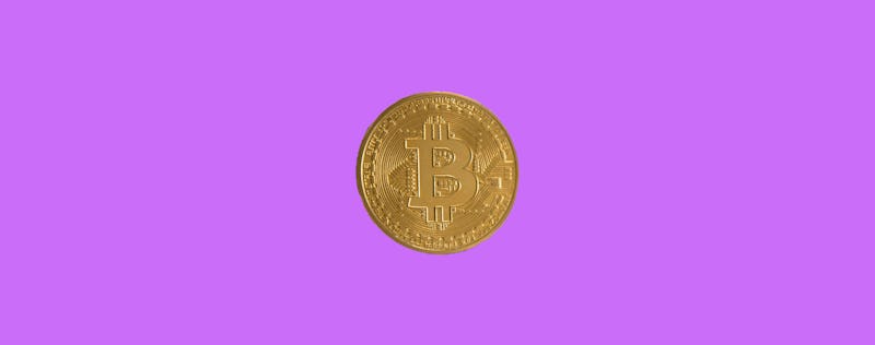 A gold bitcoin on a purple background