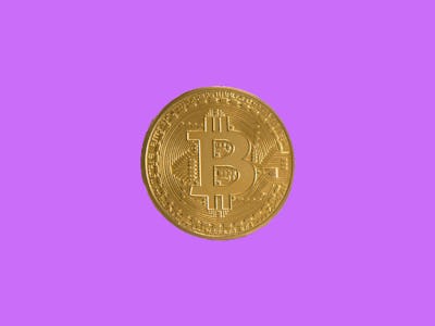 A gold bitcoin on a purple background