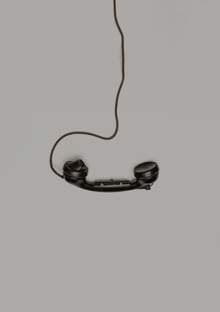 A black phone hanging from its cord